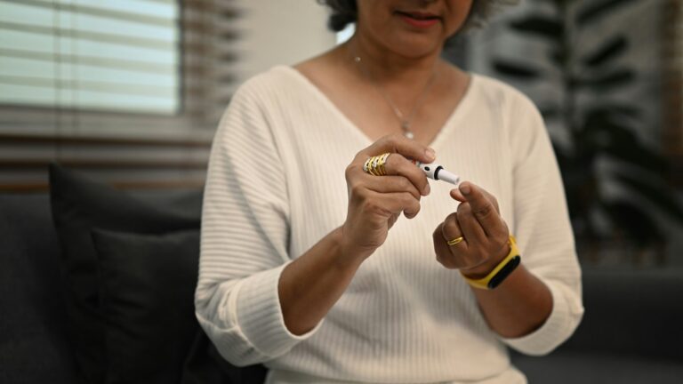 Diabetic senior woman taking blood sample with lancet pen. Diabetes and health care concept.