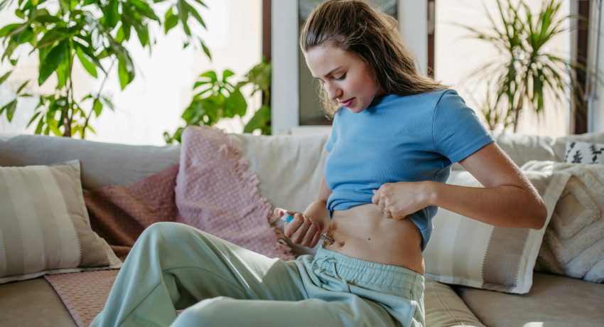 Diabetic woman injecting insulin into her abdomen.