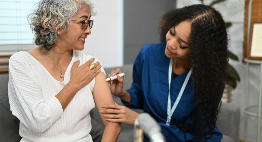 Doctor injecting diabetes treatment into upper arm of diabetic senior woman.